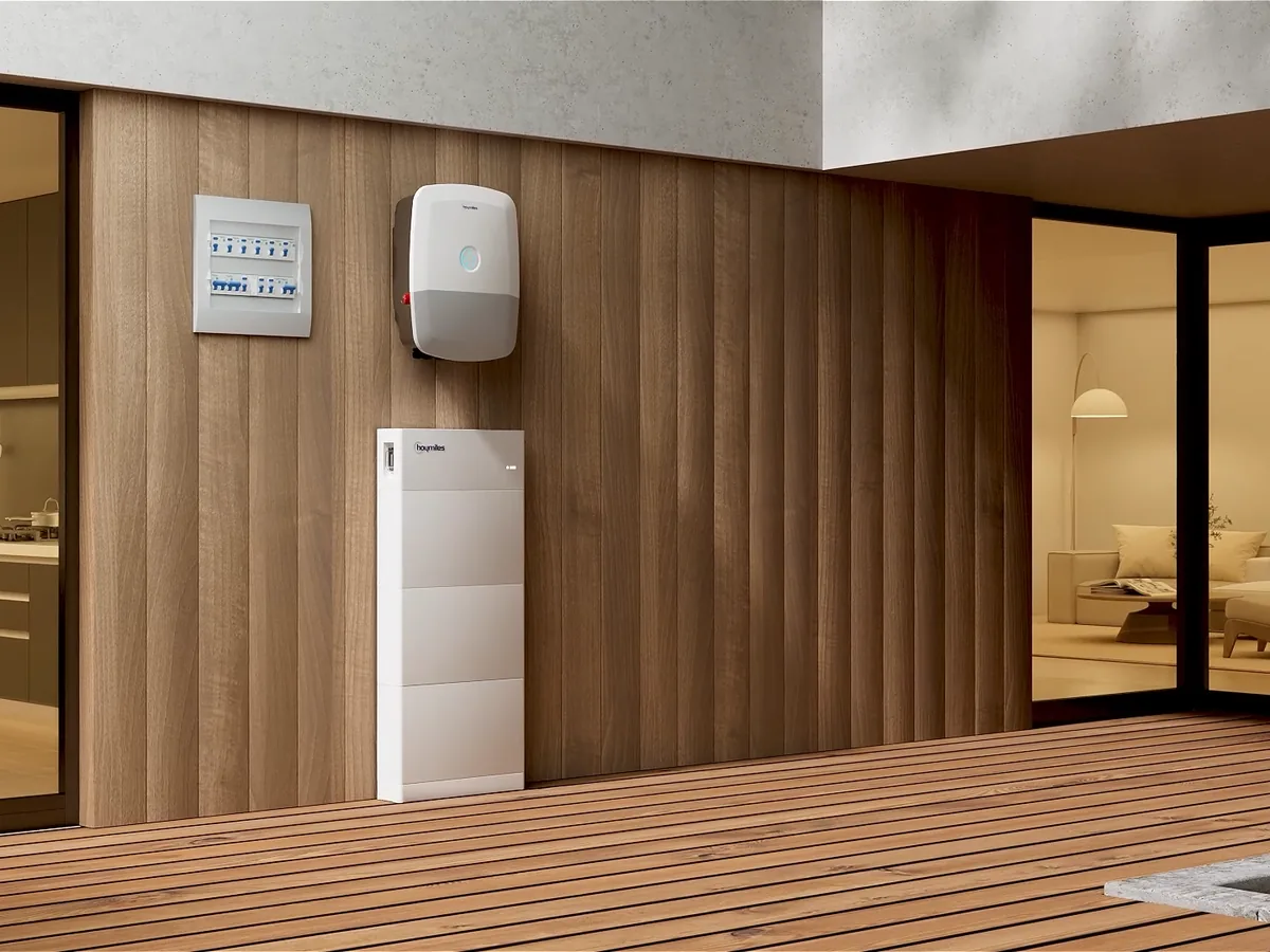 Hoymiles HIT-Wechselrichter mit LED-Ring an einer Holzwand, darunter ein Stapelspeicher der Generation G2