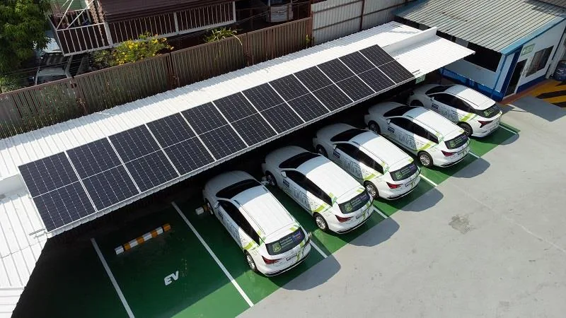 Luftbild des Carports einer Farbenfabrik in Samut Prakan, Thailand: PV-Module auf dem Carportdach, darunter Firmenfahrzeuge auf Ladeplätzen