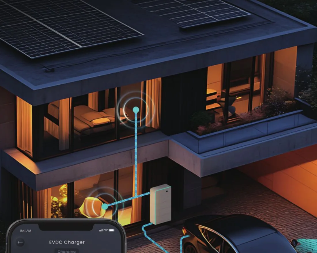 Wohnhaus mit Photovoltaikdach bei Nacht, angeschlossenes Elektrofahrzeug in der Einfahrt
